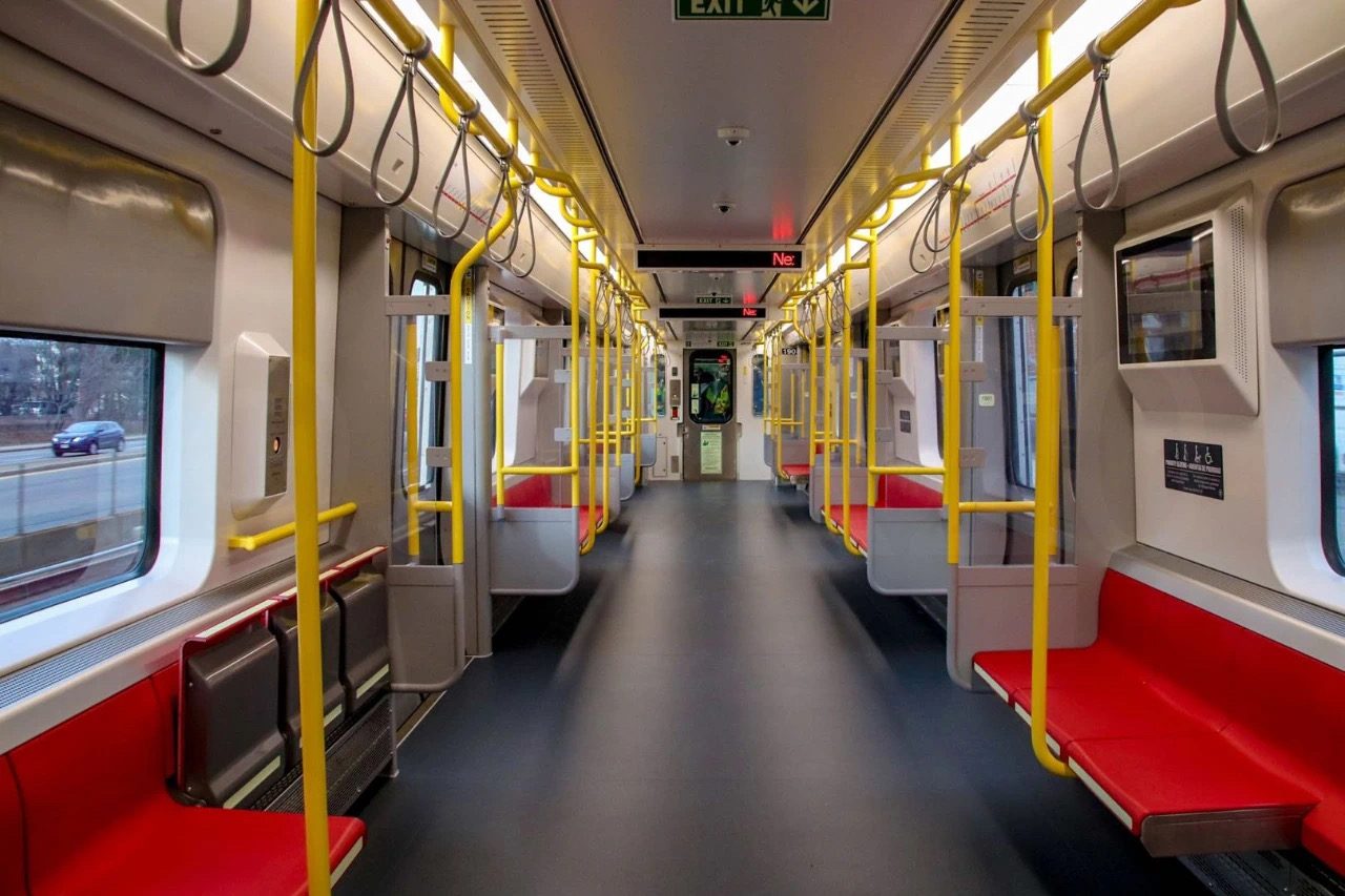 Interior of a new MBTA Red Line car with red seating and yellow handrails